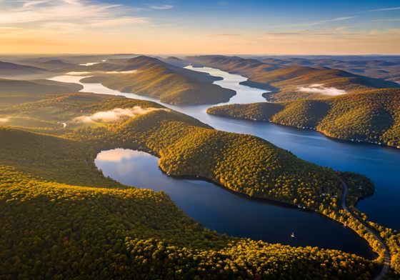 Sweeping aerial view of the long, thin Finger Lakes surrounded by lush green hills.
