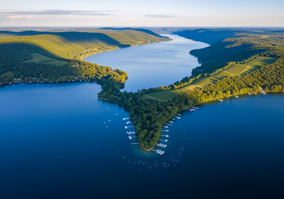 An aerial photograph of Keuka Lake, clearly showing its unique Y-shape with lush green hills surrounding the deep blue water.