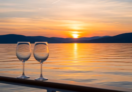 A romantic sunset over Keuka Lake, with the sky painted in orange and purple hues, viewed from the deck of a boat.